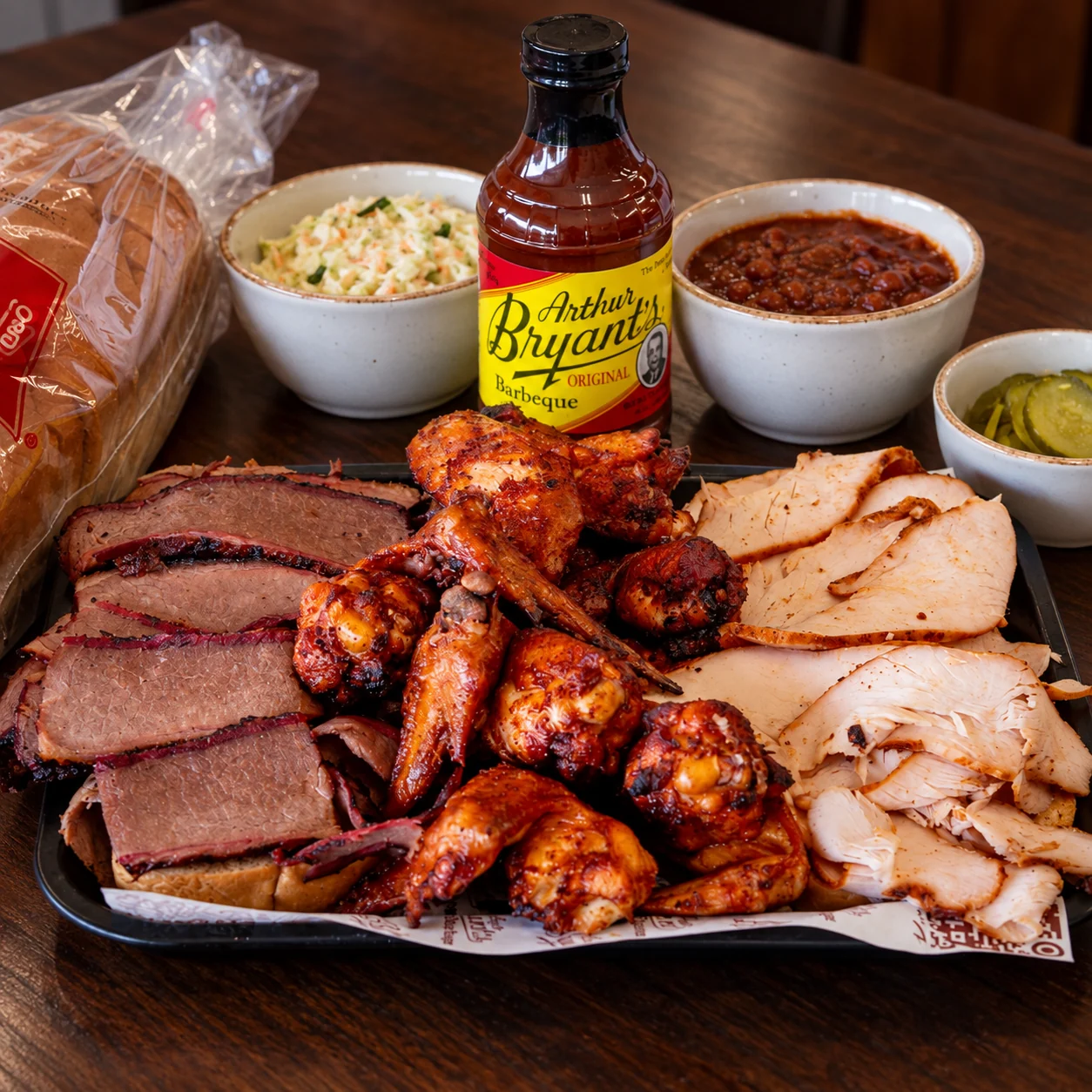 The Brooklyn Platter with brisket, turkey, wings, sides, pickles, bread, and Arthur Bryant’s Original sauce